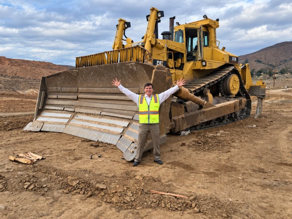 Brian Woods standing in front of a Caterpillar bulldozer on a development site