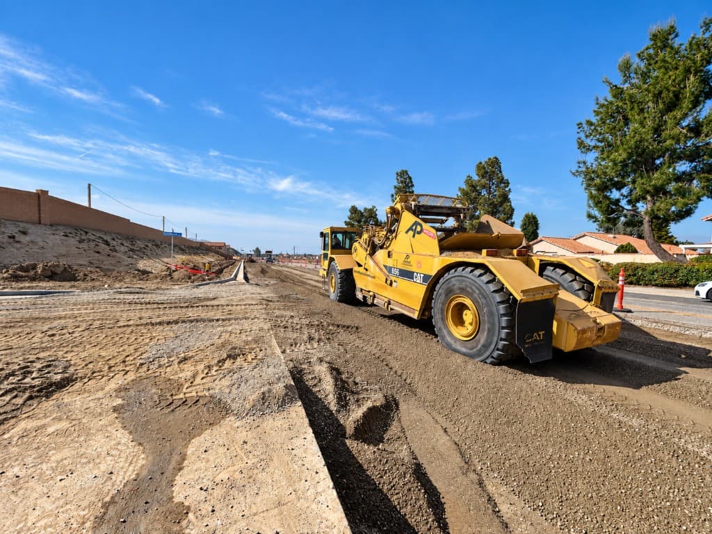Motor scraper grading a street alignment next to existing homes
