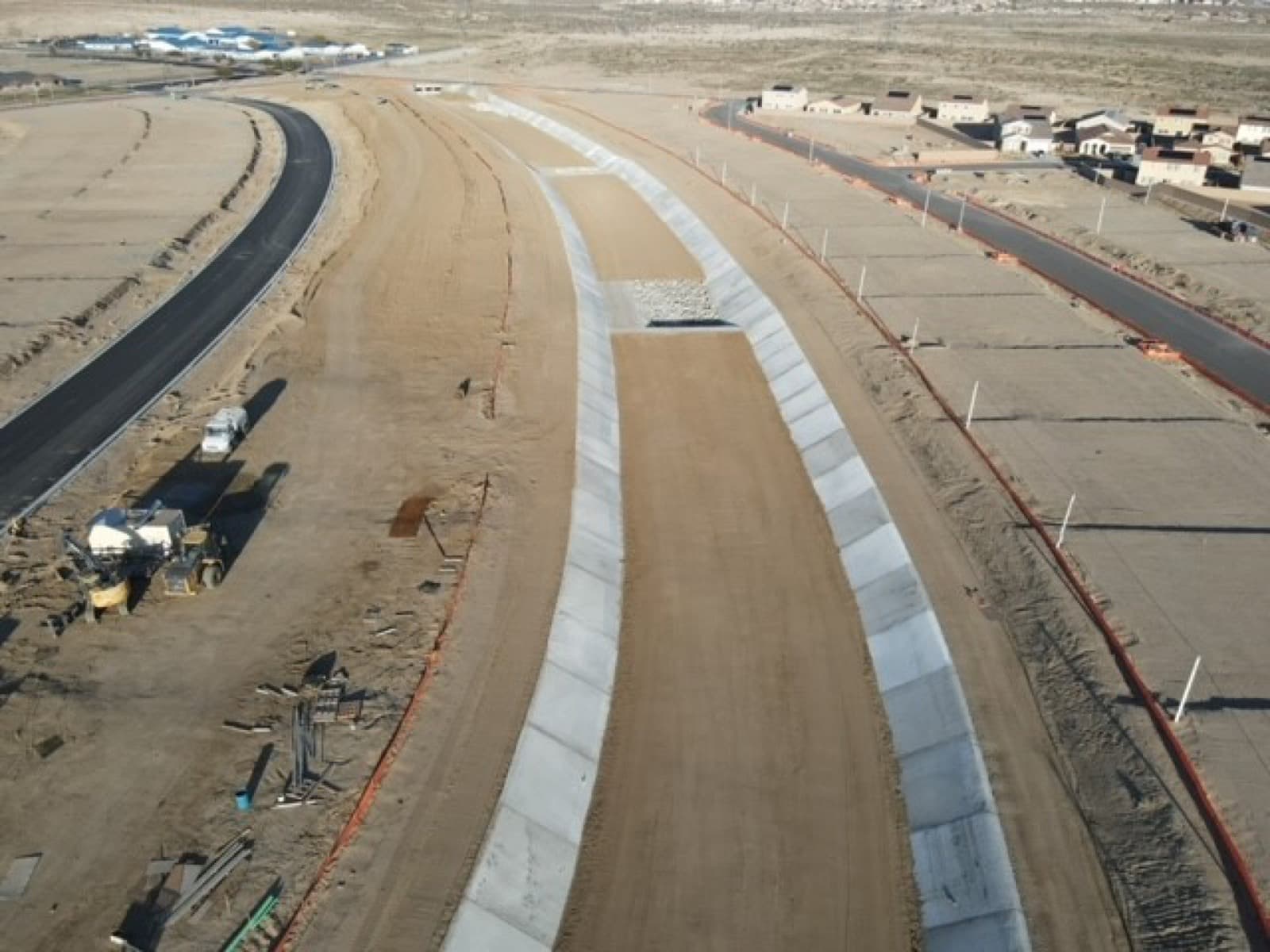 Aerial view of a concrete drainage channel between new roads and graded pads