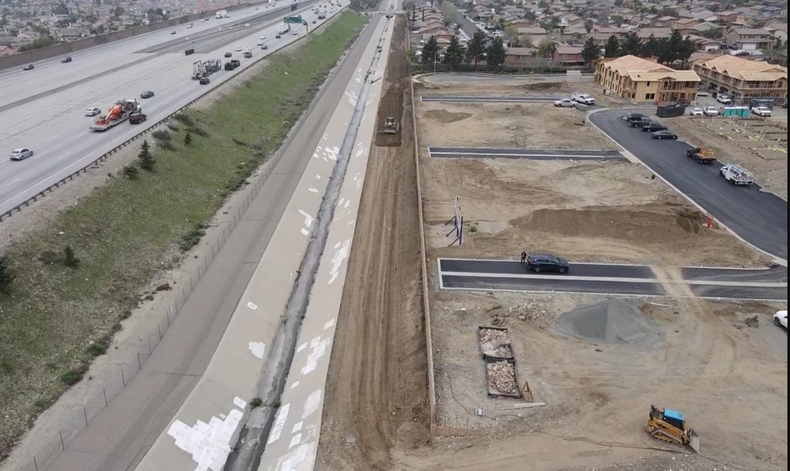 Graded residential lots beside a concrete drainage channel during fill and refinish