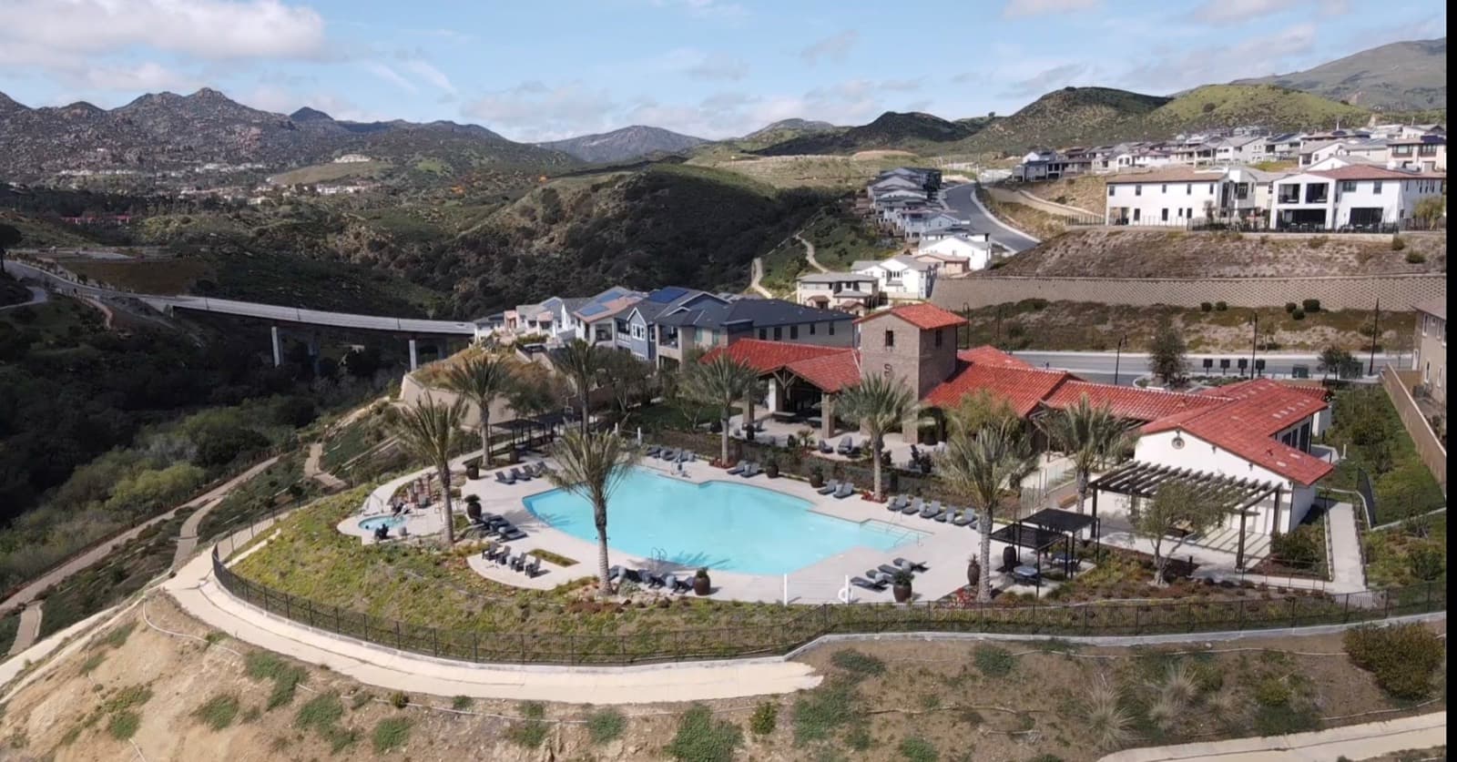 Deerlake Poema clubhouse and pool with new homes and a bridge in the background