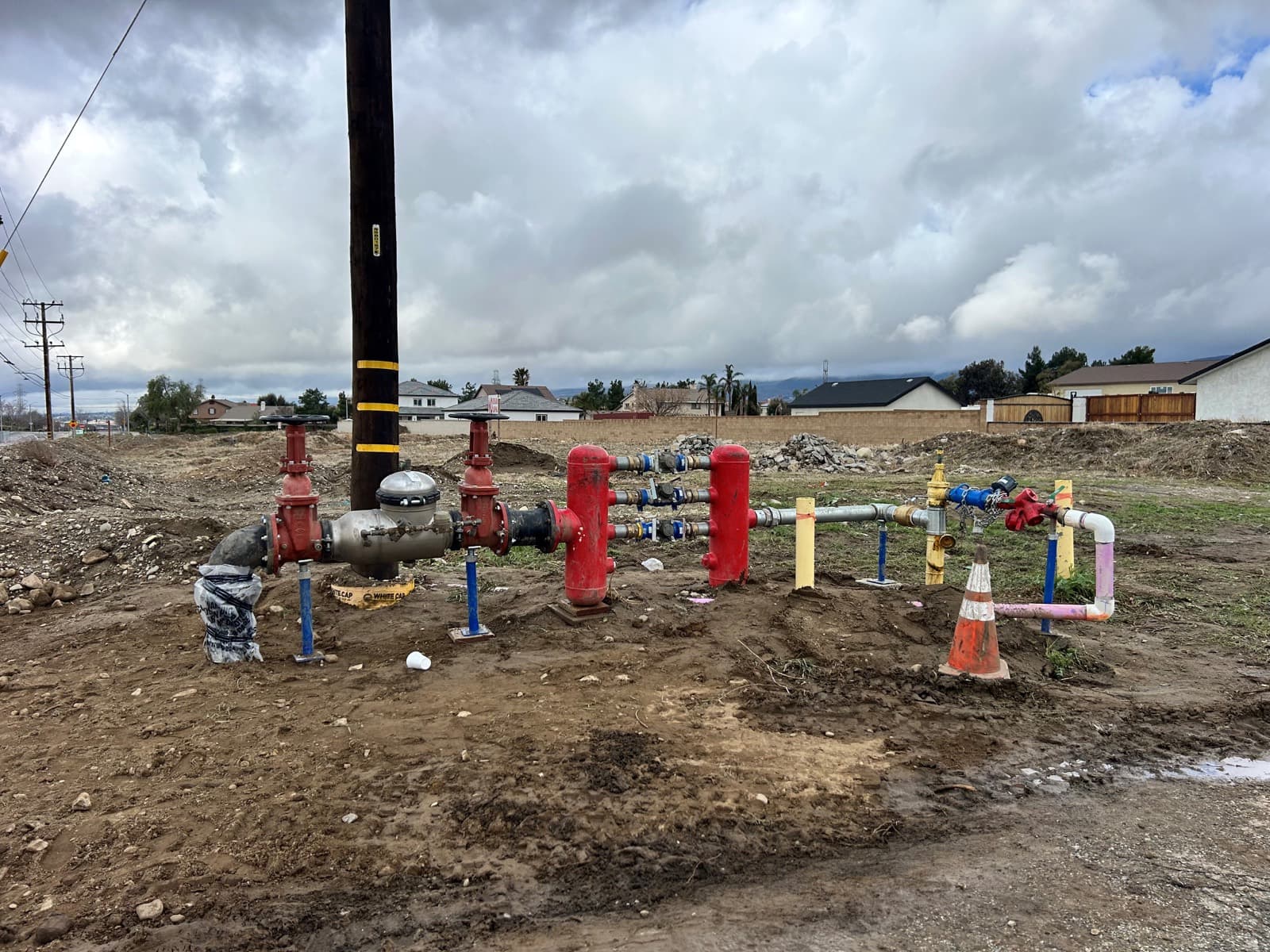 White temporary fire-line pipe along the curb in front of homes under construction